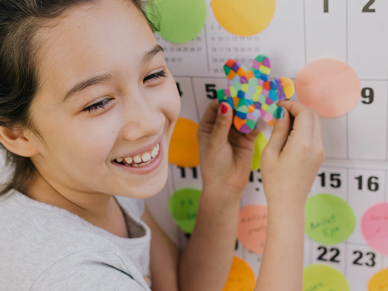 A girl smiling in front of a calendar