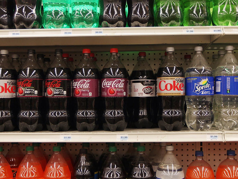 Store shelf full of Coke, Canadian Dry, Sprite and other sodas