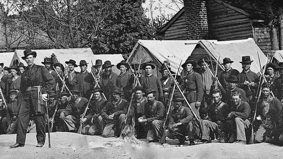 Soliders kneeling behind 2 other soldiers in civil war era.