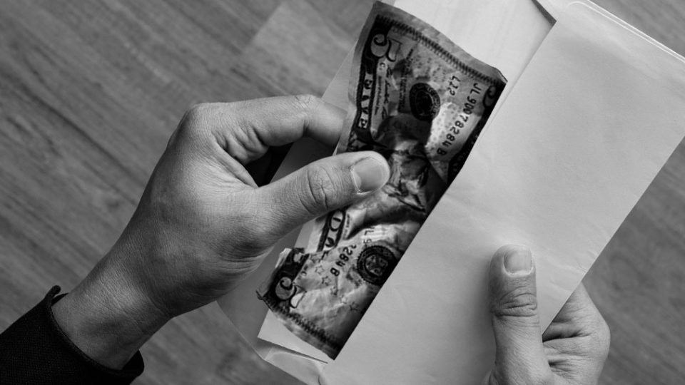 Person pulling out 5 dollar bill from white envelope