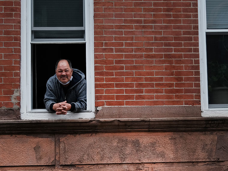 A smiling person leans out of their window