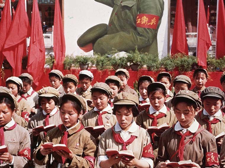 A group of children in uniform reading from small red books