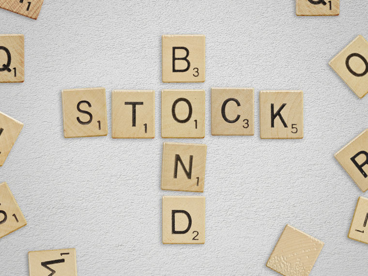 Lettered wooden pieces arranged to spell the words "stock" and "bond". The two words share a single "O" piece.