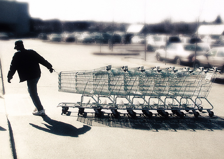Man in shadow pulling a line of grocery carts
