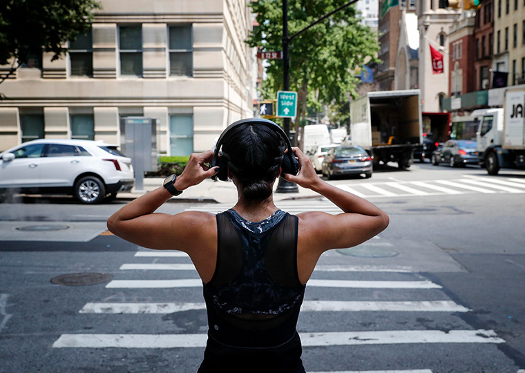 Woman with headphones stands in crosswalk