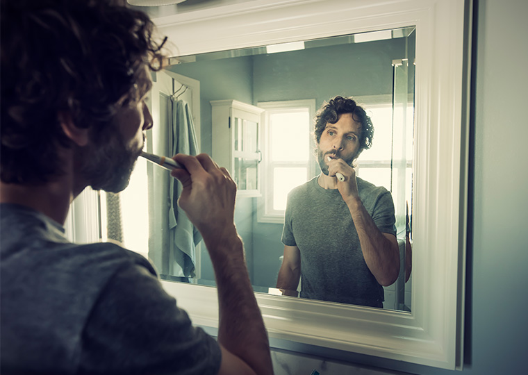 Reflection in the mirror of man brushing his teeth