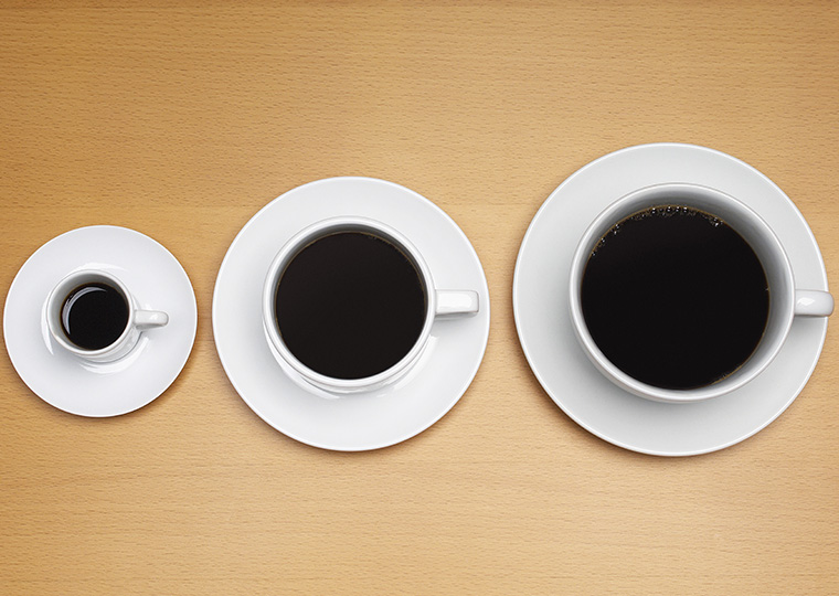 A small, medium and large cup of black coffee each in a white cup on a white saucer