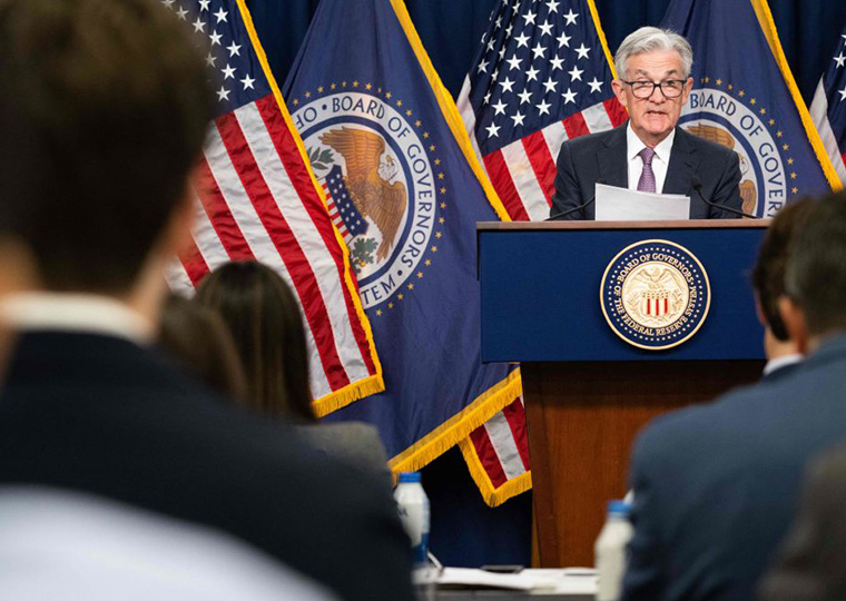 Fed Chair Jerome Powell stands at a podium and answers questions from the press