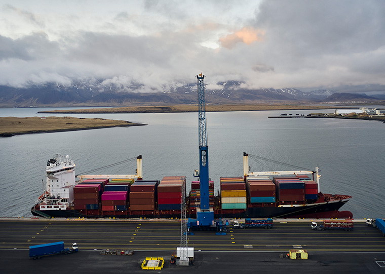 A cargo ship loaded with cargo container sits at a dock in Iceland
