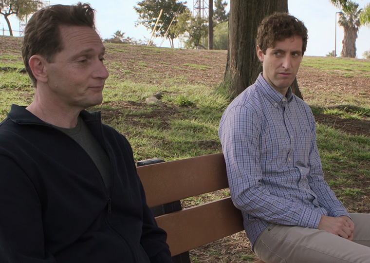 Two men sit on a bench in a scene from the TV show "Silicon Valley."