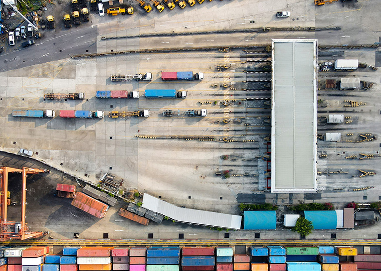 An overhead view of shipping containers and semi trucks going through a gate
