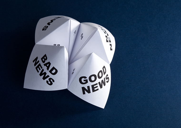 A folded paper fortune teller gsme with good news written on one flap and bad news written on another in black lettering.