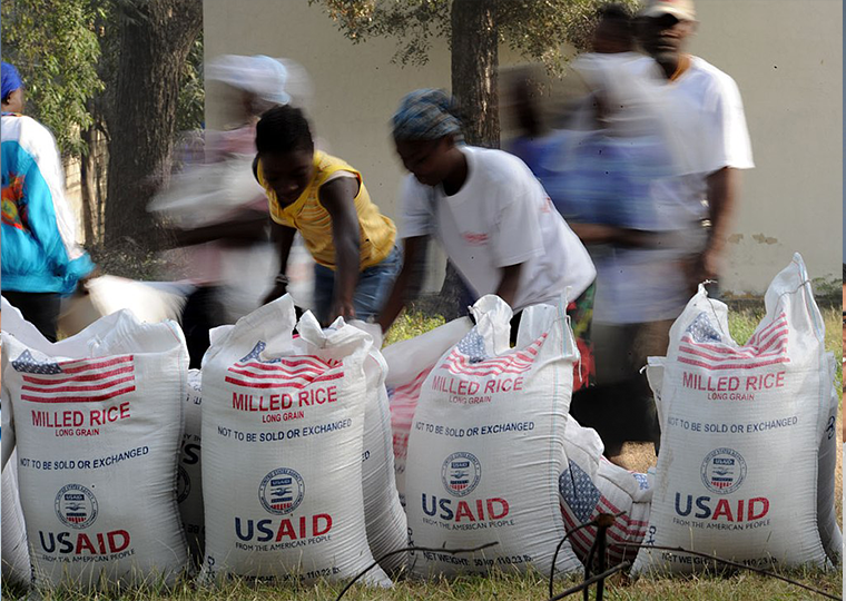 Haitian citizens take 100-pound bags of rice at an aid distribution point in Port-au-Prince, Haiti.