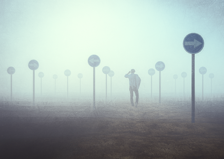 A man is lost in a foggy field with blue signs all around him.