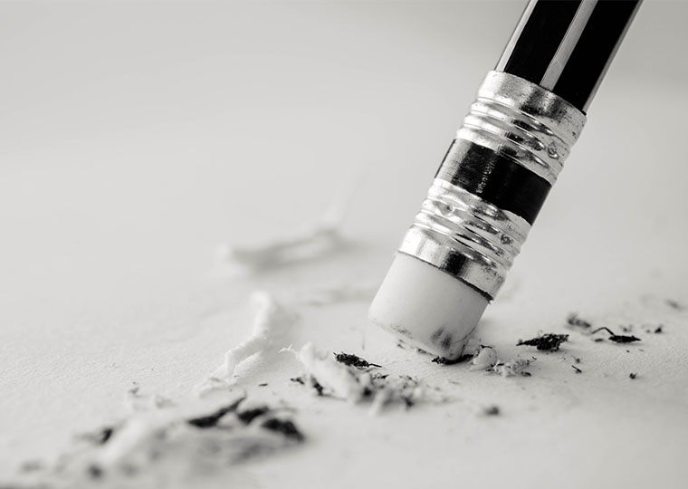 Black pencil with white eraser removing a written mistake on a piece of paper.
