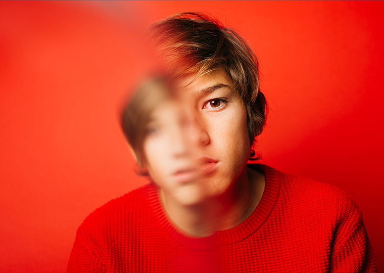 Pre-adolescent boy wearing in red over a red background with a cool attitude.
