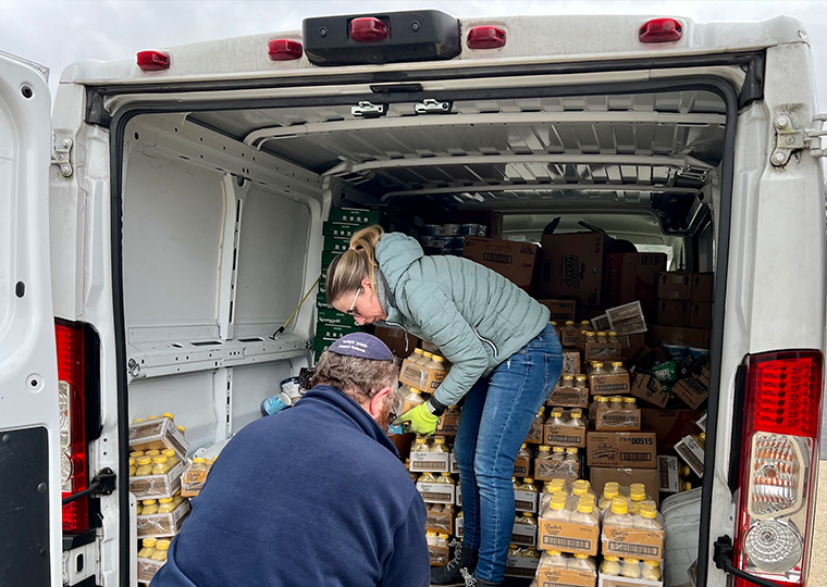 A woman hands off cases of drinks to a male volunteer.