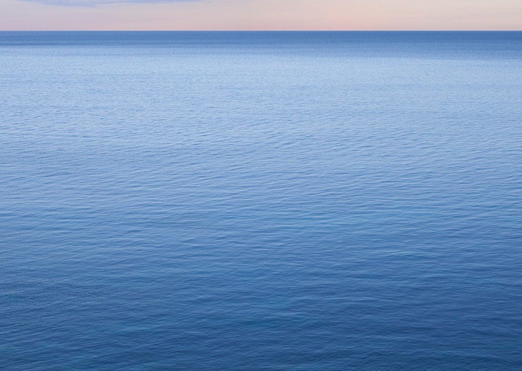 Calm blue ocean water with a sliver of horizon above it.