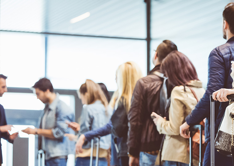 Group of people standing in queue to board airplane.