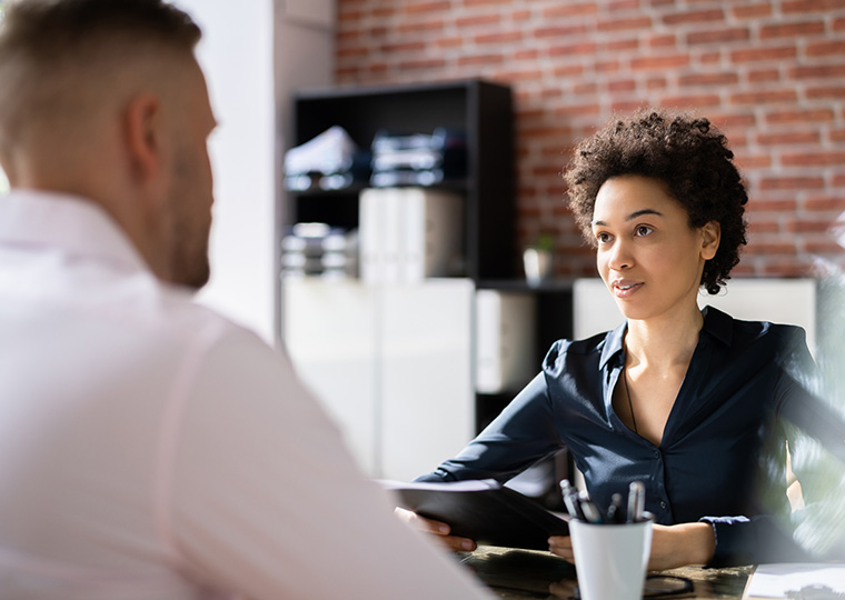 Mature businesswoman taking an interview of man over the wooden desk in office