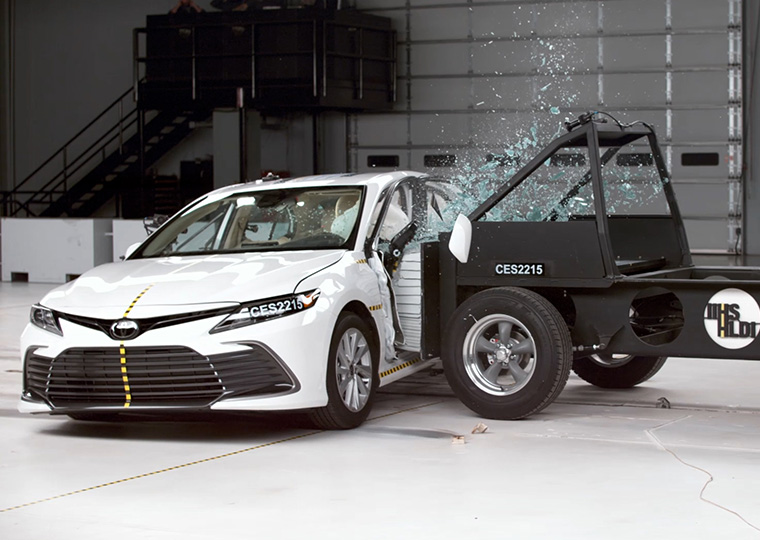 A white sedan in a crash test taking impact to driver side dooor.