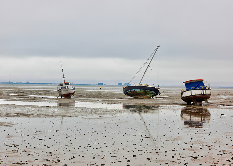 Four boats on a beach on a foggy day at low tide