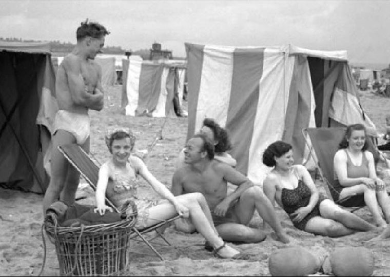 Black and white photo of of people relaxing on the beach at South Shields, August 1950.